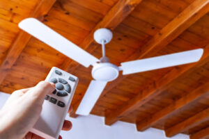 A three blade ceiling fan hangs off a wooden ceiling.